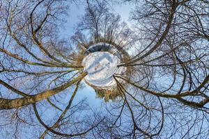 piccolo pianeta. vista panoramica aerea sferica a 360 gradi nella foresta invernale in una giornata di sole invernale su sfondo blu foto