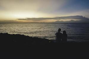 shilloutte di una coppia romantica che frequenta una spiaggia durante un tramonto foto