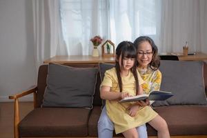 ritratto di una donna anziana e di una nipote che leggono un libro per migliorare le capacità di lettura e le attività familiari. foto