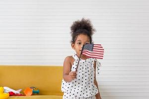bambina carina con una piccola bandiera nazionale degli stati uniti, bambina che gioca in soggiorno foto