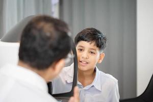 ragazzo che fa il test della vista che controlla l'esame con autorefractor in negozio di ottica, optometrista che fa il test della vista per il paziente bambino, oculista che esamina il paziente del bambino foto