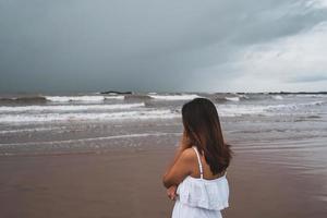 giovane donna che si sente sola e triste guardando il mare in una giornata uggiosa foto