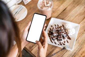 viaggiatore della giovane donna che utilizza lo smartphone nella caffetteria durante il viaggio foto