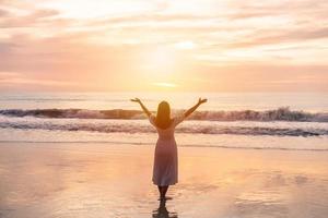 viaggiatore della giovane donna che si rilassa e si diverte sulla spiaggia tropicale al tramonto, alle vacanze e al concetto di estate foto