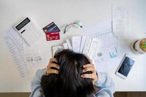 giovane donna stressata che calcola le spese mensili della casa, le tasse, il saldo del conto bancario e il pagamento delle bollette della carta di credito, il reddito non è sufficiente per le spese foto