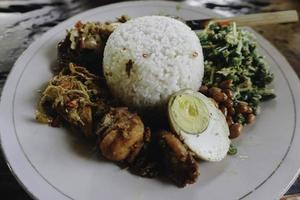 nasi campur ayam betutu. pollo arrosto balinese ripieno di foglie di manioca. accompagnato con riso al vapore, sate lilit, jukut antungan, lawar nangka e sambal matah. foto