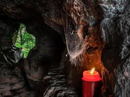 una candela brucia vicino all'uscita della grotta delle streghe sul monte saint-michel in alsazia. foto