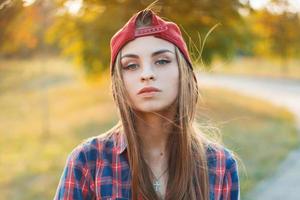 ritratto autunnale di una bella ragazza con un berretto da baseball e una maglietta al tramonto. foto