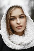 bella donna con una sciarpa lavorata a maglia bianca in testa in un parco invernale foto