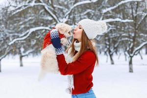 donna alla moda che tiene un cane e lo bacia foto