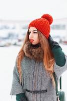 giovane ragazza in abiti caldi alla moda che cammina in una giornata invernale sullo sfondo della città foto