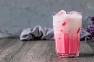 bevanda fredda al latte rosa freddo in vetro trasparente su sfondo grigio. latte tailandese foto