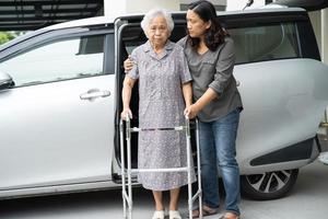 badante figlia aiuta e sostiene asiatica anziana o anziana signora paziente prepararsi a uscire dalla sua auto. foto