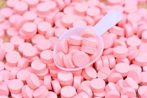 molte pillole rosa con il cucchiaio per il concetto di assistenza sanitaria foto