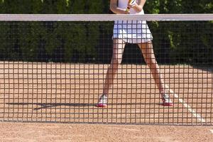 gambe sottili dell'atleta di tennis femminile dietro la barriera a rete