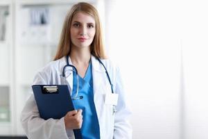 Ritratto di medico donna con cartella in corridoio dell'ospedale foto