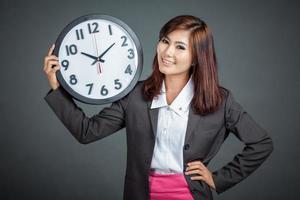 la donna di affari asiatica tiene un orologio e sorride