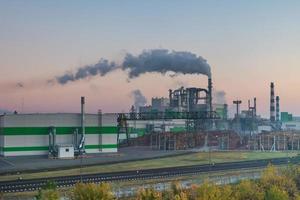 tubi della segheria della pianta di impresa di lavorazione del legno nell'alba del mattino. concetto di inquinamento atmosferico. paesaggio industriale inquinamento ambientale rifiuti di centrale termica foto