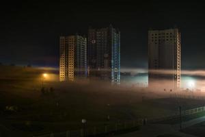 panorama notturno della zona residenziale con grattacieli nella nebbia al mattino presto foto