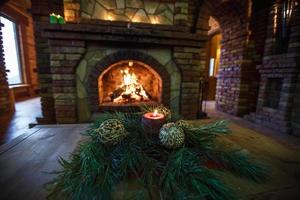 candele di natale palle e rami di abete su un tavolo di legno vicino al camino. umore festivo foto