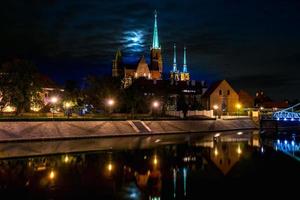 riflessione panoramica con vista lunare della città vecchia architettura e argine del fiume oder e quartiere storico ostrow tumski con le guglie illuminate della cattedrale gotica di wroclaw, polonia foto