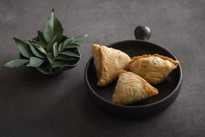 samosa indiano tradizionale, famoso per gli spuntini su fondo scuro. primo piano foto