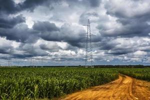 silhouette delle torri del pilone elettrico ad alta tensione sullo sfondo sulla strada gialla con belle nuvole foto