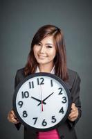 la donna di affari asiatica tiene un orologio e sorride