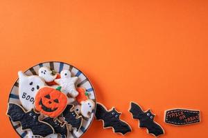 vista dall'alto dei biscotti di zucchero a velo decorati festivi di halloween su sfondo arancione. foto