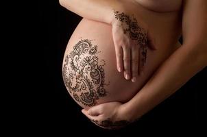 tatuaggio del hennè sulla pancia e sulle mani incinte di una donna foto