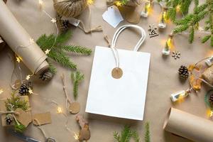 confezione regalo per natale e capodanno in materiali ecologici carta kraft, rami di abete vivo, pigne, spago. tag con mock up, arredamento naturale, fatto a mano, fai da te. copia spazio. piatto, sfondo foto