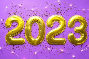 felice anno nuovo- numeri d'oro 2023 su sfondo viola con paillettes, stelle, glitter, luci di ghirlande. saluti, cartolina. calendario, copertina. foto