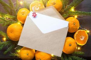 busta con un foglio di carta: una lettera a babbo natale, copyspace su uno sfondo natalizio di mandarini, ghirlande, rami di abete. molletta da bucato in posizione per le note. capodanno, lista dei desideri, sogno, regali foto