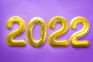 felice anno nuovo- numeri d'oro 2022 su sfondo viola con paillettes, stelle, glitter, luci di ghirlande. saluti, cartolina. calendario, copertina. foto