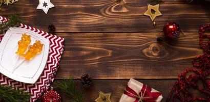due lecca-lecca su bastone a forma di simbolo del nuovo anno 2021 - toro su piattino bianco, asciugamano con ornamenti e decorazioni natalizie su sfondo di legno. stelle gioielli, perline, palla, abete. disteso, copia spazio foto