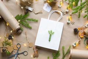 confezione regalo per natale e capodanno in materiali ecologici carta kraft, rami di abete vivo, pigne, spago. tag con mock up, arredamento naturale, fatto a mano, fai da te. copia spazio. piatto, sfondo foto