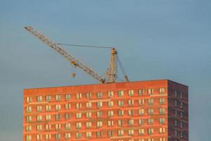 sollevare la gru sopra l'edificio nel tramonto contro il cielo blu foto