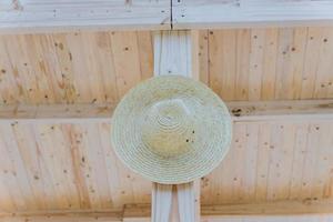 cappello di paglia da donna appeso al palo di legno foto