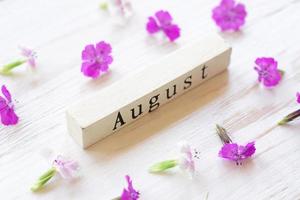 vista dall'alto del calendario in legno con segno di agosto e fiori rosa. foto