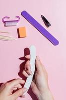 donna limare le unghie. mani femminili e strumenti per manicure. cura delle unghie professionale, cura di sé. fai la manicure da solo, allineando le unghie con una lima per unghie. manicure a casa foto