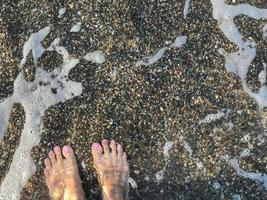 un paio di piedi di donna su uno sfondo di spiaggia di ciottoli foto