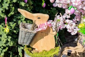 coniglietto di legno di pasqua seduto in un muschio su un barilotto di legno come decorazione, all'aperto foto