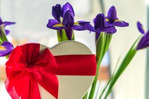 bellissimo bouquet di iridi blu e scatola regalo a forma di cuore con fiocco in pizzo rosso foto