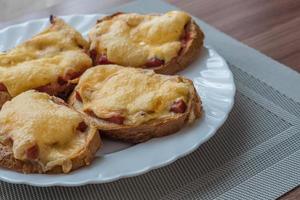 primo piano di panini caldi al forno con formaggio e salsiccia sul piatto bianco foto