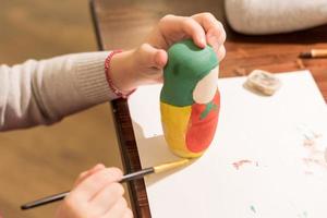 la bambina dipinge la bambola russa di nidificazione chiamata matrioshka con vernice gialla foto