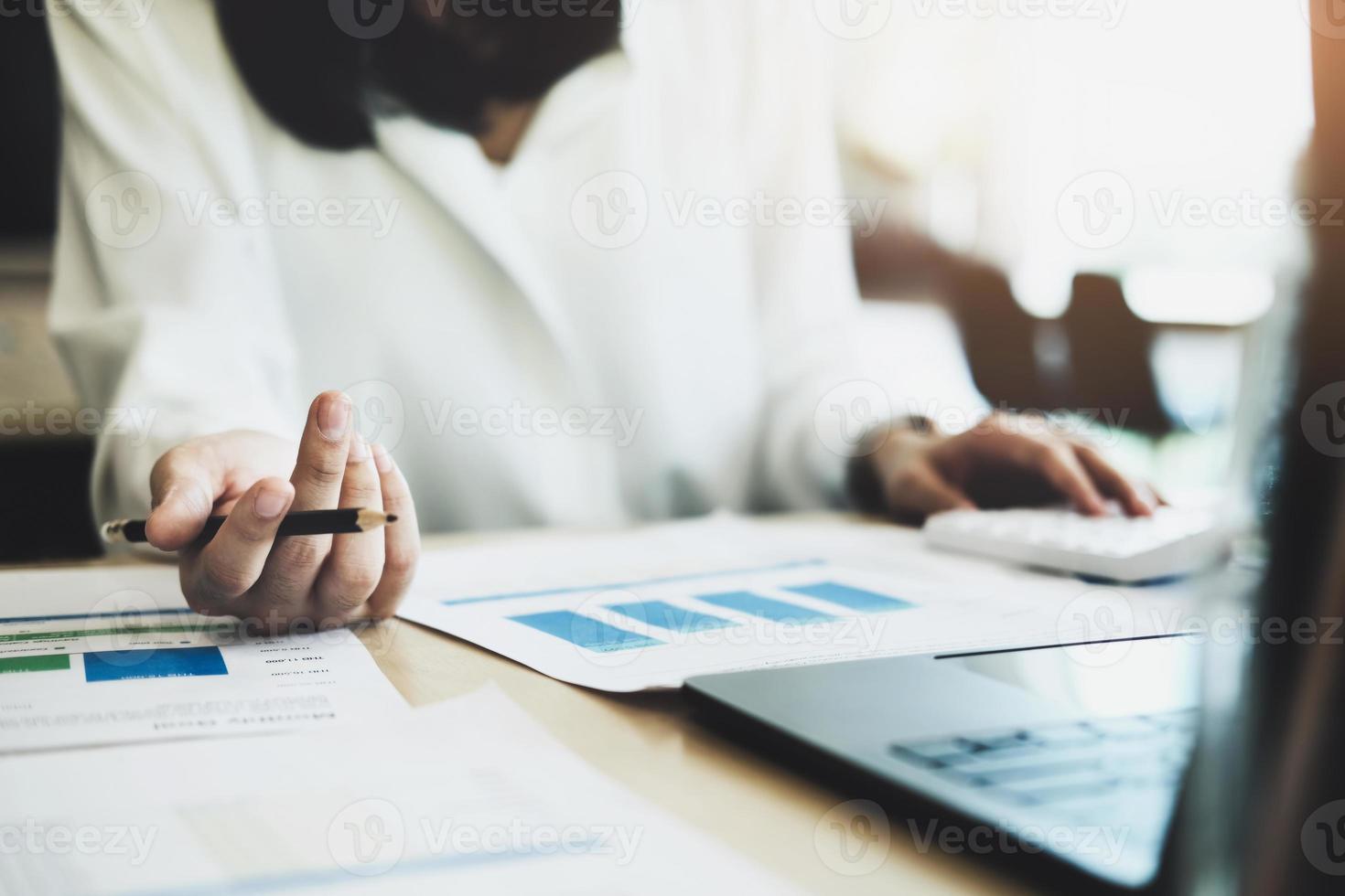 foco mulher segurando um lápis auditores usam calculadoras de documentos orçamentários para encontrar erros de desembolso do orçamento anual. foto