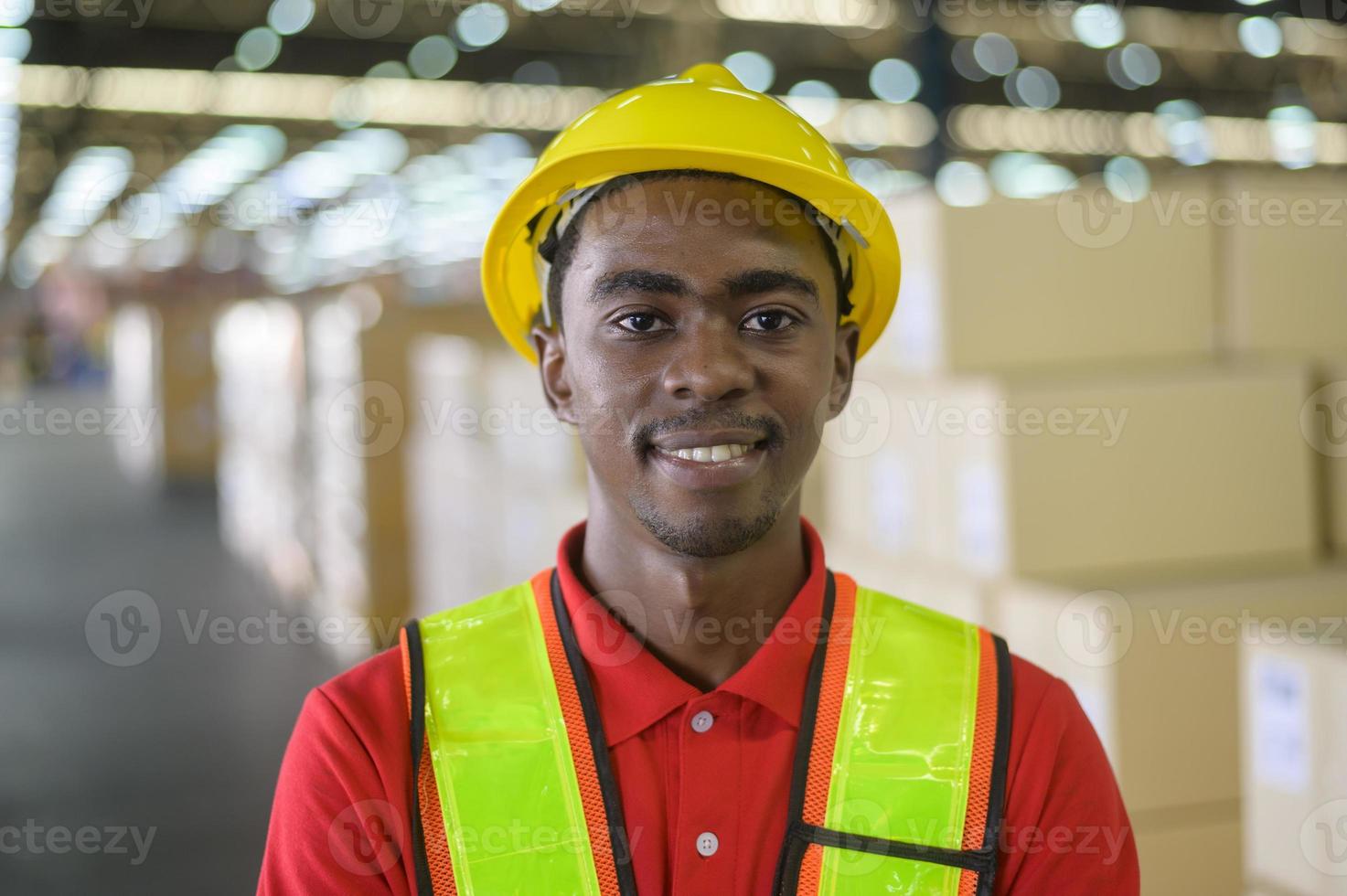 retrato de jovem trabalhador masculino de raça mista usando capacete no moderno armazém de armazenamento de loja de varejo foto