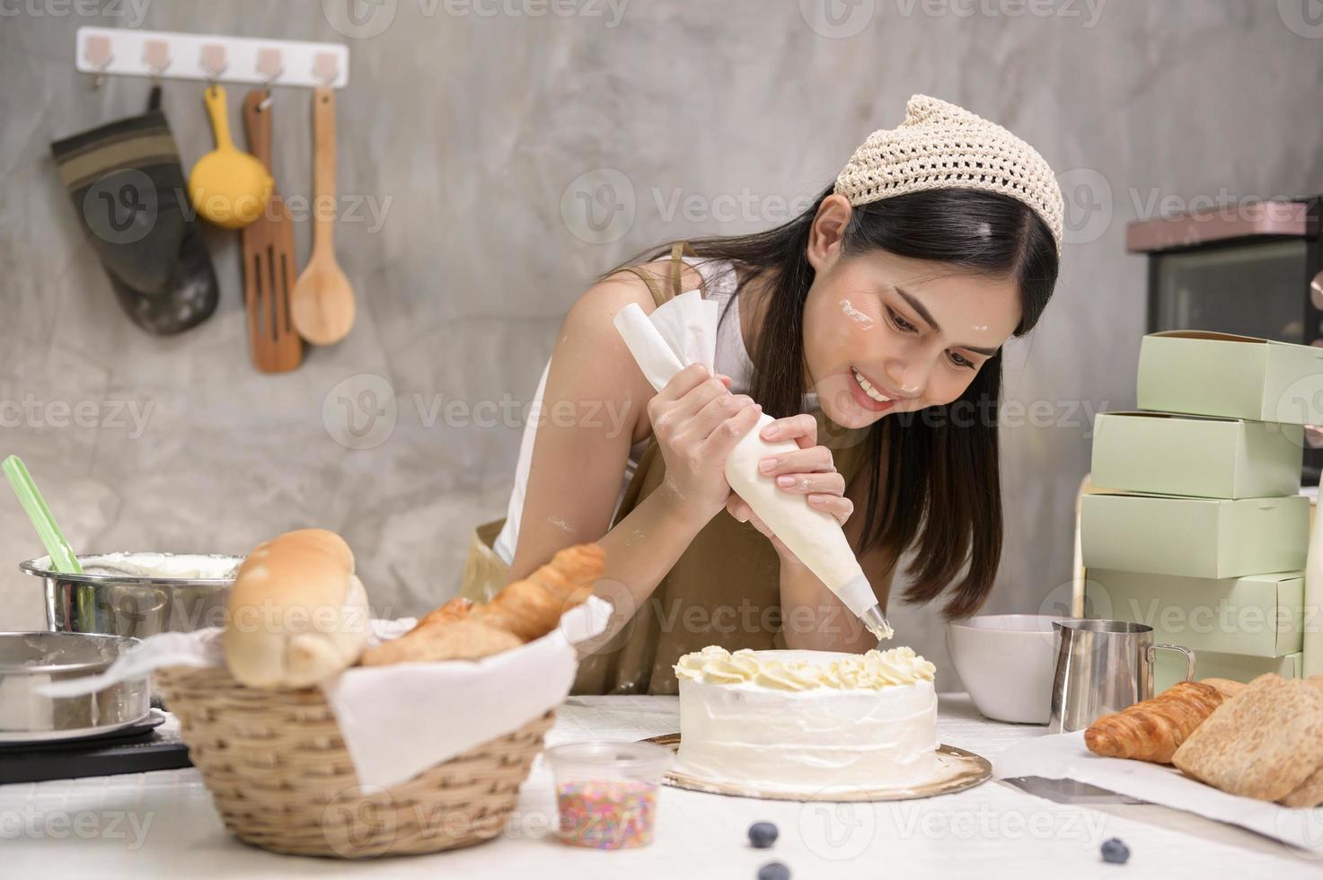 jovem mulher bonita está assando em seu negócio de cozinha, padaria e cafeteria foto