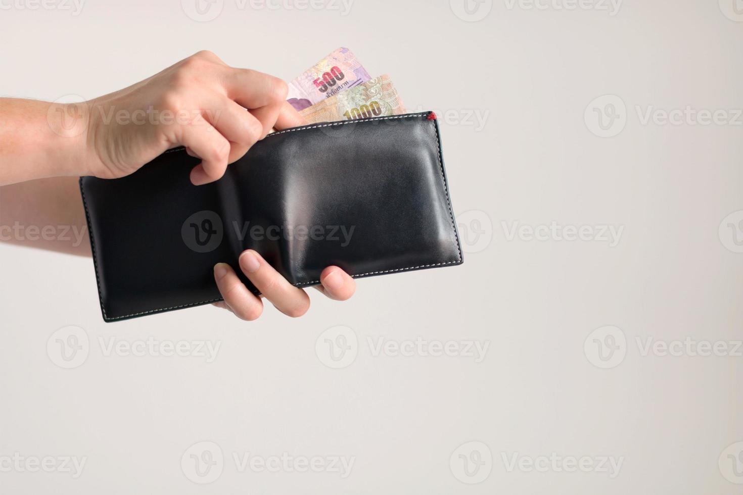 mãos pegando dinheiro em baht tailandês da carteira para pagar. foto