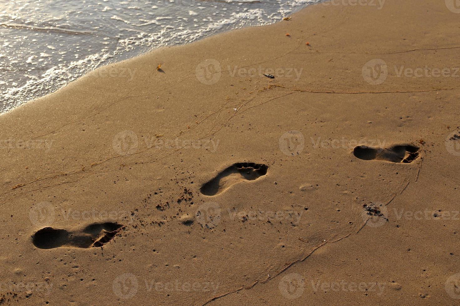 pegadas na areia na praia da cidade. foto